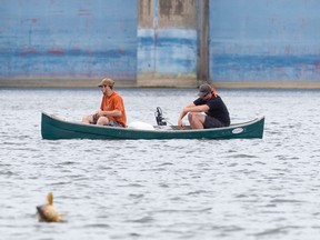 A fish breaks the surface of Fanshawe Lake, unbeknownst to two nearby fishers in a canoe in London. Talk about the one that got away! (CRAIG GLOVER, The London Free Press)