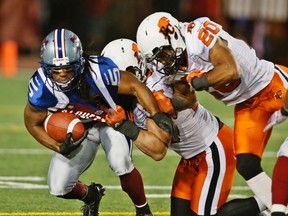 Montreal Alouettes Larry Taylor (L) is tackled by BC Lions Keynan Parker (20) and Jason Arakgi during second half CFL football action in Montreal, July 4, 2014. (REUTERS/Christinne Muschi)