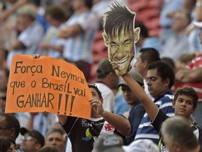 Fans hold a picture of Brazilian player Neymar and a sign reading " Go Neymar Brazil will win" before a quarter-final football match between Argentina and Belgium at the Mane Garrincha National Stadium in Brasilia during the 2014 FIFA World Cup on July 5, 2014. (AFP PHOTO / JUAN MABROMATA)