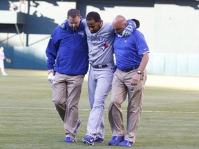 Edwin Encarnacion #10 of the Toronto Blue Jays is assisted off the field by trainers after sustaining an injury during the first inning against the Oakland Athletics at O.co Coliseum on July 5, 2014 in Oakland, California. (Jason O. Watson/Getty Images/AFP)