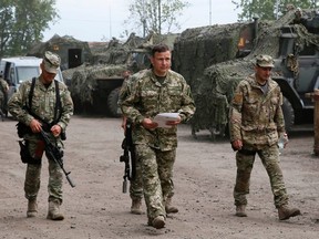 Newly-appointed Ukrainian Defence Minister Valery Heletey (C) walks with troops at a temporary base near the city of Slaviansk July 6, 2014. REUTERS/Gleb Garanich