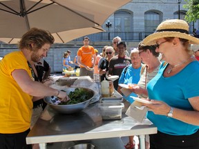 Eric Brennan, left, sous chef at Le Chien Noir Bistro, helps serve the samples of wild boar terrine and smoked beets after Saturdays Local Food, Local Chefs cooking demo by chef Derek MacGregor in the courtyard of Springer Market Square. (Julia McKay/The Whig-Standard)