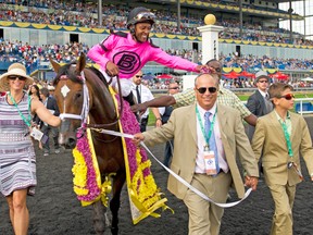Trainer Mark Casse has some flowers playfully put on his head by jockey Patrick Husbands following their Queen’s Plate victory on Sunday. (Michael Burns photo)