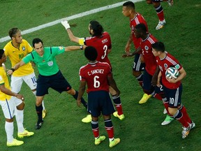 Spanish referee Carlos Velasco Carballo (C) intervenes to stop an argument among players during the quarter-final football match between Brazil and Colombia at the Castelao Stadium in Fortaleza during the 2014 FIFA World Cup on July 4, 2014. AFP PHOTO / POOL / FABRIZIO BENSCH