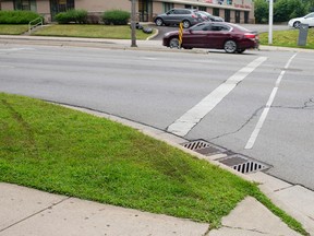Tire marks streak across the grass towards the spot where a man and woman were struck by a car after it left the road while travelling west on Oxford Street at Talbot Street around 6 p.m. Sunday.  The woman has been released from hospital, while the male remains admitted in fair condition, according to police.  The intersection is pictured here in London, Ontario on Monday July 7, 2014.
(CRAIG GLOVER/The London Free Press/QMI Agency?)