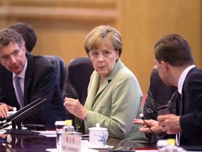 German Chancellor Angela Merkel, centre, chats with her delegates as she attends a bilateral meeting with Chinese Premier Li Keqiang (not pictured) at the Great Hall of the People in Beijing July 7, 2014. (REUTERS/Andy Wong/Pool)