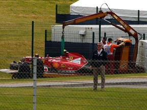The car of Ferrari Formula One driver Kimi Raikkonen of Finland is lifted off the track following a crash during the British F1 Grand Prix at the Silverstone Race circuit, central England July 6, 2014. (REUTERS)