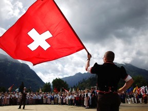 File photo of a boy dressed in traditional a costume waving a Swiss national flag during the official ceremonial act at the 28th Federal Yodelling Festival in Interlaken June 19, 2011.
 REUTERS/Pascal Lauener/Files