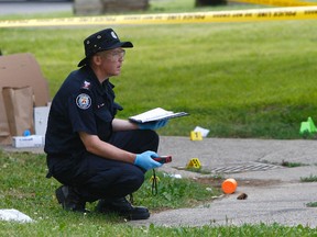 A Toronto police forensics officer gathers evidence outside of 11 Flemington Rd. (CHRIS DOUCETTE, Toronto Sun)
