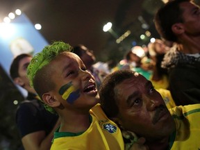 A Brazilian boy fan cries next to his father as they watch a broadcast of the 2014 World Cup semi- final soccer match between Brazil and Germany in Sao Paulo, July 8, 2014.  REUTERS/Nacho Doce (BRAZIL  - Tags:  SOCCER SPORT WORLD CUP)