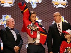 Aaron Ekblad puts on a team jersey after being selected as the number one overall pick by the Panthers at the NHL Draft in Philadelphia on June 27, 2014. (Bill Streicher/USA TODAY Sports)