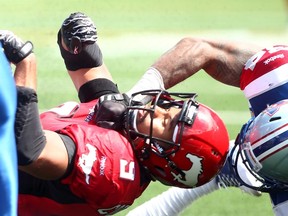 Stampeders' Jon Cornish takes a nasty hit from Alouettes' Kyries Hebert during CFL action in Calgary on June 28, 2014. (Darren Makowichuk/QMI Agency)