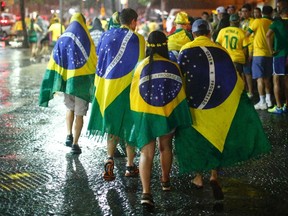 Brazil soccer fans walk in the rain after watching a broadcast of their team's loss against Germany in their 2014 World Cup semi-final match, in Rio de Janeiro July 8, 2014. (REUTERS/Jorge Silva)