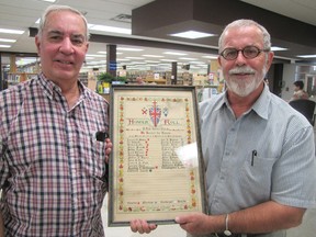 George Pitfield, left, lay minister of St. Clair United Church in Aamjiwnaang, received a World War II honour roll listing church members who enlisted, from Chatham historian Jerry Hind on Wednesday.