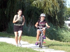 Anne Fournier takes part in a 5km run at Crothers Conservation Area on June 30, as Loni Shobway rides alongside her. The run was a fundraiser for the Haitian Children's Rescue Mission orphanage.