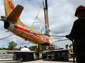 Master Cpl. Dave Rehberg helps guide the path of an F-86 Sabre jet fuselage as a crane lifts it at CFB Trenton Wednesday. Crews tested the fuselage's fit with its wings, bottom, in preparation for its return this August to West Zwicks Island Park in neighbouring Belleville.