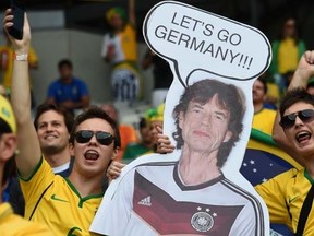 Brazilian fans hold a cardboard cutout of Mick Jagger before the semi-final football match between Brazil and Germany at The Mineirao Stadium in Belo Horizonte during the 2014 FIFA World Cup on July 8, 2014. AFP PHOTO / VANDERLEI ALMEIDA