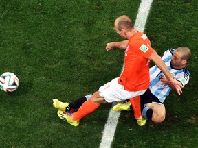 Argentina's Javier Mascherano apparently tore his anus on this game-saving tackle against Netherlands winger Arjen Robben during their World Cup semifinal match Wednesday. (Reuters)