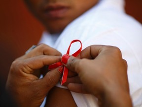 A red ribbon is put on the sleeves of a man by his friend to show support for people living with HIV during a program to raise awareness about AIDS on World AIDS Day in Kathmandu December 1, 2013. (REUTERS/Navesh Chitrakar)