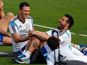 Argentina's Martin Demichelis (left) and Ezequiel Lavezzi laugh next to teammate Lionel Messi (right, bottom) during a training session ahead of their World Cup final against Germany, in Vespasiano, Brazil on Thursday, July 10, 2014. (Marcos Brindicci/Reuters)