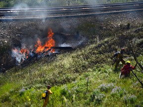 Local firefighters and ESRD wildfire crews respond to a fire beside Canadian Pacific Railway train tracks between Lundbreck, Alta., and Burmis, Alta., in the afternoon on Thursday, July 10. John Stoesser photos/QMI Agency.