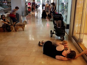 A woman lies with her baby on the floor of a shopping mall as an air raid siren, warning of incoming rockets, sounds in Tel Aviv July 10, 2014.   REUTERS/Daniel Bar-On