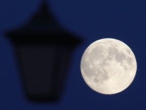 The moon rises behind the street lamp in St. Petersburg June 22, 2013. The largest full moon of the year, called the "supermoon," will light up the night sky this weekend. REUTERS/Alexander Demianchuk