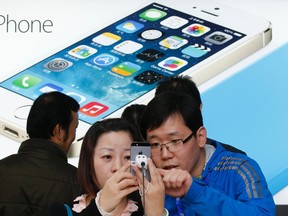 A staff of a China Mobile shop (R) explains a function of the iPhone 5s to a customer in Beijing Jan. 17, 2014. REUTERS/Kim Kyung-Hoon