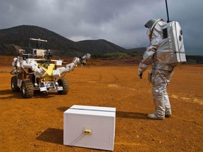 A person wearing a Mars suit Aouda.X prototype walks towards Mars rover Eurobot of the European Space Agency (ESA) during testing in the semi-desert of Rio Tinto, Spain, in this April 20, 2011 file photo. (REUTERS/OeWF/Paul Santek/Handout)