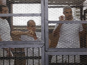 Al Jazeera journalists (L-R)  Baher Mohamed, Peter Greste and Mohammed Fahmy stand behind bars in a court in Cairo.

REUTERS/Asmaa Waguih/Files