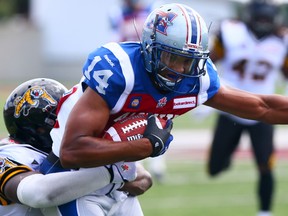 Abraham Kromah was given up by the Hamilton Tiger-Cats but refused to let go of Brandon London of the Montreal Alouettes during preseason CFL action June 14, 2014. (Dave Abel/Toronto Sun/QMI Agency)