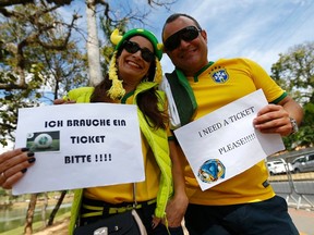 Brazilian fans searching for tickets for the  semi-final match Brazil against Germany, hold placards outside Estadio Mineirao in Belo Horizonte July 8, 2014. (REUTERS/Kai Pfaffenbach)