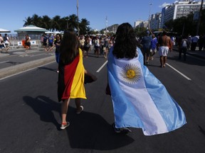 Fans wearing national flags of Germany and Argentina over their shoulders, walk on Copacabana beach, prior to the 2014 World Cup final match Rio de Janeiro, July 13, 2014. (REUTERS/Marcos Brindicci)