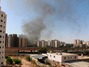 Smoke rises near buildings after heavy fighting between rival militias broke out near the airport in Tripoli July 13, 2014. Heavy fighting broke out between rival militias near the airport of the Libyan capital Tripoli on Sunday, residents and officials said, reporting explosions and gunfire that forced the suspension of all flights.  REUTERS/ Hani Amara