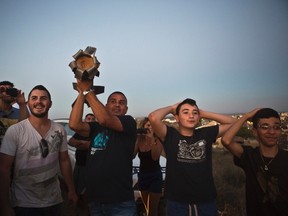 An Israeli man holds up part of a rocket that was fired towards Israel from the Gaza Strip as he watches rocket-fire together with others from a hill near Sderot July 13, 2014.  REUTERS/Nir Elias