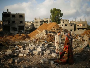 Palestinians stand amongst the rubble of Tayseer Al-Batsh's family house, which police said was destroyed in an Israeli air strike in Gaza City July 13, 2014.  REUTERS/Mohammed Salem