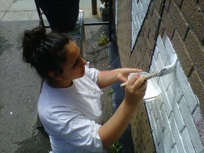 Tanya Haddad, 14, paints a mural in an alley along Montreal Rd. near Vanier Pkwy. on Monday, July 14, 2014. Artist Nicole Belanger is collaborating with a group of teens thanks to a grant from Crime Prevention Ottawa. 
KELLY ROCHE/OTTAWA SUN