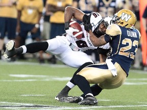 Marcus Henry #16 of the Ottawa RedBlacks is tackled by Desia Dunn #23 of the Winnipeg Blue Bombers in second half action in a CFL game at Investors Group Field on July 3, 2014 in Winnipeg, Manitoba, Canada