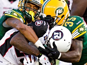 Rennie Curran, right, and Dexter McCoil tie up RedBlacks ball carrier Chevon Walker during Friday's game at Comonwealth Stadium. (Codie McLachlan, Edmonton Sun)