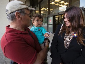 Grandfather Livio Fent (left) holds Quentin Morin, brother of 2-year-old Geo Mounsef, alongside Quentin's mother Sage Morin outside the Edmonton Law Courts Building after the preliminary inquiry for Richard Suter wrapped up for the day in Edmonton, Alta. on Monday, July 14, 2014. (Ian Kucerak/Edmonton Sun/QMI Agency)