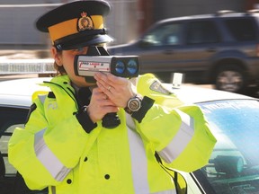 An officer with Wood Buffalo RCMP points a radar gun at traffic in this 2014 file photo. Amanda Richardson/Fort McMurray Today/Postmedia Network