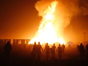 Burning Man participants walk towards the Temple of Whollyness as it burns at the conclusion of the 2013 Burning Man arts and music festival in the Black Rock desert of Nevada, late September 1, 2013. REUTERS/Jim Bourg