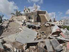 A Palestinian man walks atop the rubble of a house which police said was destroyed in an Israeli air strike in Gaza City July 15, 2014. REUTERS/Ahmed Zakot