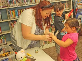 Greer Macdonell, children's services co-ordinator with the Lambton County Library, helps Sabrynah Guitar, 4, repurpose a toy at a Toy Hacking program at Sarnia's Mallroad Library. Looking on is program participant Devin Branton, 8. (DAVID PATTENAUDE, QMI Agency)