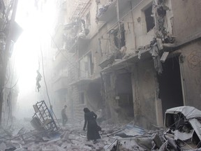 A Syrian woman makes her way through debris following a air strike by government forces in the northern city of Aleppo on July 15, 2014. (AFP PHOTO)