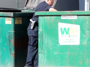 A police officer looks in a Dumpster. (Winnipeg Sun files)