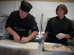 James Meadows chops some greens while his wife and business partner Mary Meadows watches inside the new test kitchen at 300 S. Edgeware Rd. in St. Thomas on Tuesday, July 15, 2014. The test kitchen is meant to be an incubator for food entrepreneurs and a place to test recipes. (Ben Forrest, Times-Journal)