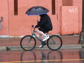 Gino Donato/The Sudbury Star   
A cyclist shields himself rom the rain as he makes his way down Elgin Street on Tuesday afternoon. About 25 mm of rain was expected with more today and a high of only 15. The forecast for Thursday calls for sun and cloud and a high of 22.