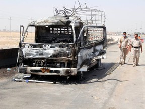 Policemen inspect a burnt-out vehicle at the site of a bomb attack at a checkpoint in the city of Kirkuk July 12, 2014. On the southern edge of Kirkuk province, where thousands of displaced have fled from the city of Tikrit and other areas overrun by militants last month, 18 civilians were killed and 26 more severely wounded on Friday when a suicide bomber drove a car into a checkpoint, police and medics said. (REUTERS/Ako Rasheed)