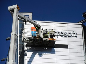 Workers install the logo of U.S. technology giant Microsoft on the wall of Nokia's former headquarters in Espoo, Finland April 26, 2014. REUTERS/Mikko Stig/Lehtikuva